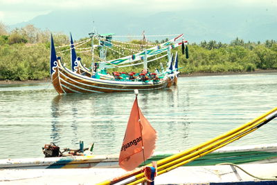 Men sitting on boat in lake against sky