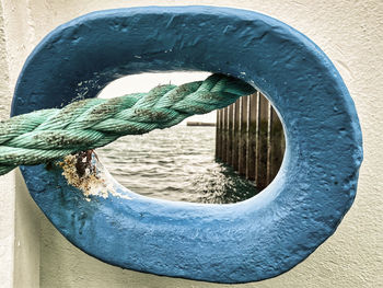 Close-up of rope hanging on metal against wall