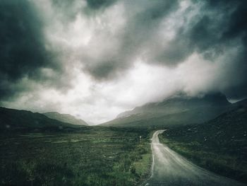 Scenic view of road by mountains against sky