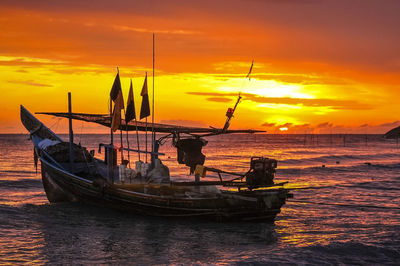 Silhouette fishing boat in sea against orange sky
