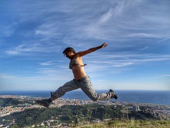 Energetic woman leaping in mid-air against sky