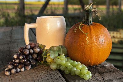 Close-up of grapes by cup and wet pumpkin on table