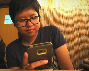 Close-up of young man using smart phone while sitting at home