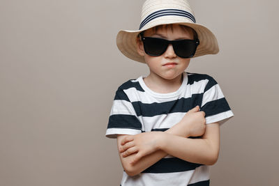 Boy wearing sunglasses standing against gray background
