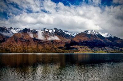 Scenic view of lake by snowcapped mountains against sky