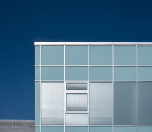 Low angle view of modern building against blue sky