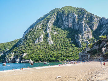 Scenic view of beach and mountains against clear blue sky