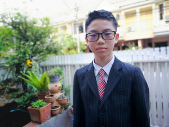 Portrait of boy wearing eyeglasses while standing against house