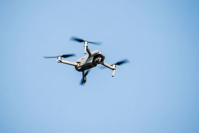 Low angle view of airplane flying against clear blue sky