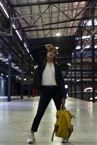 Portrait of businesswoman with backpack standing at railroad station