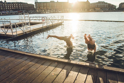 Men on pier over lake against sky