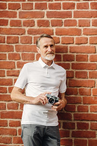 Full length of man photographing against brick wall