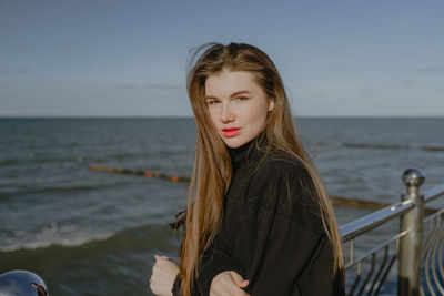 Portrait of young woman against sea