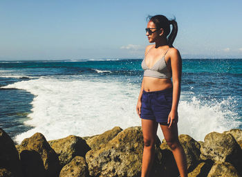 Full length of young woman standing by sea against sky