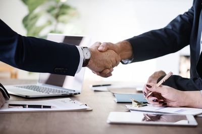 Cropped image of businessman shaking hands with male coworkers in office