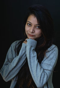 Close-up portrait of young woman against black background