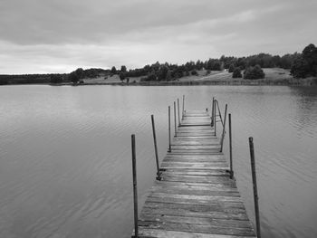 Wooden pier over lake against sky