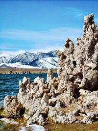 Snow covered rocks by sea against sky