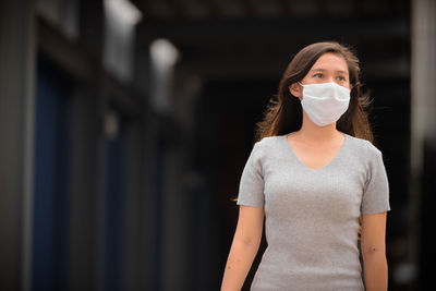 Beautiful woman looking away while wearing mask outdoors