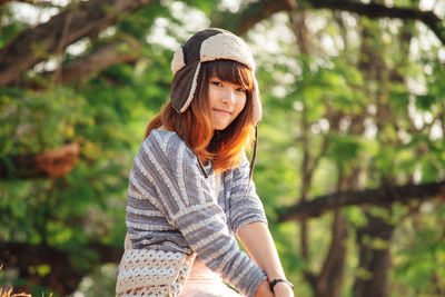 Portrait of woman wearing hat against trees