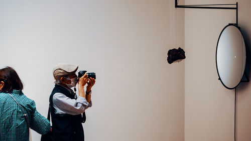 Midsection of woman photographing against wall