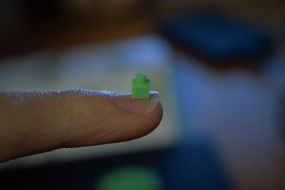 Cropped hand of woman holding toy block on finger