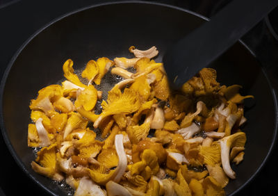 High angle view of golden chanterelle mushrooms in a sizzling frying pan. 