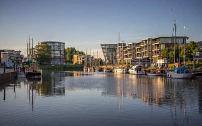 Fishing boats in river at harbor against clear sky