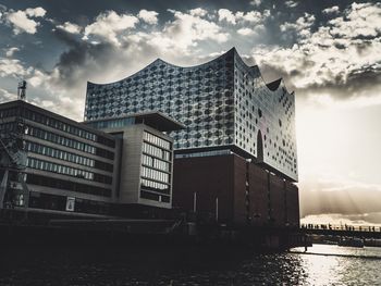 Buildings by river against sky in city