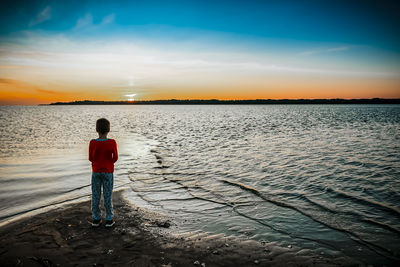 7 years old boy watching the sunrise on a summer day