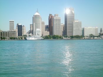 Sea by buildings in city against sky