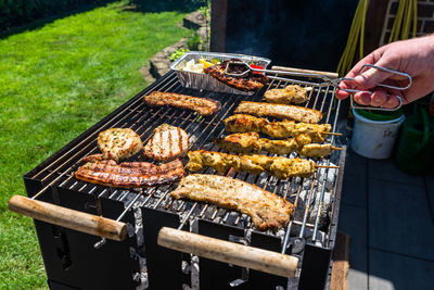 Different types of meat fried on the home grill, standing on a home garden on the paving stone.