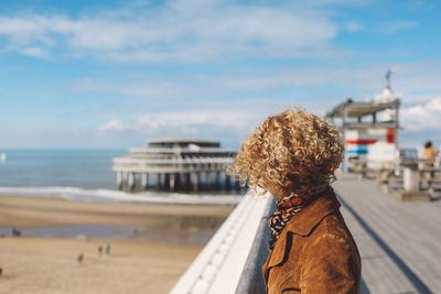 Side view of woman standing on scheveningen pier at beach during sunny day