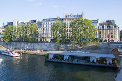 Bridge over river by buildings in city against sky