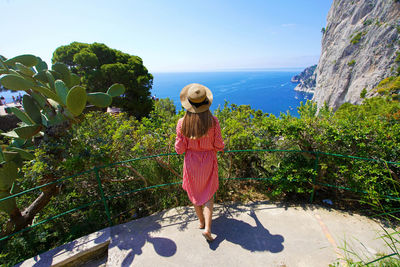 Woman enjoying landscape from balcony in the gardens of augustus on capri island, italy
