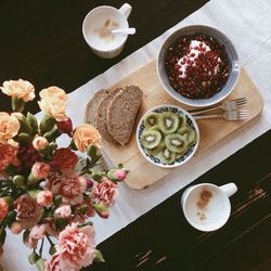 Directly above shot of breads with kiwi and coffee cups on table