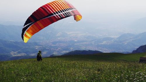 Woman paragliding over mountains against sky