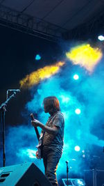 Side view of musician playing guitar during music festival