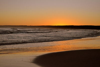 Scenic view of beach against clear sky during sunset
