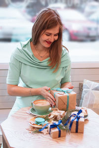 Young smiling pregnant woman in cafe with cup of coffee and christmas gifts. pregnant lifestyle.