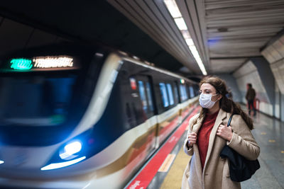 Woman wearing mask standing on railroad station platform