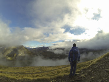 Rear view of man walking on mountain against sky