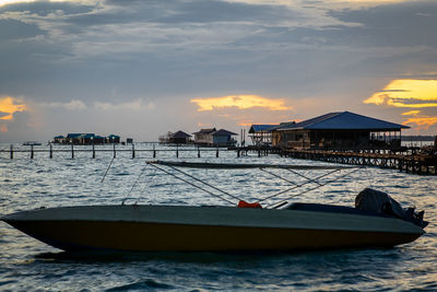 Sailboat moored on sea against sky during sunset