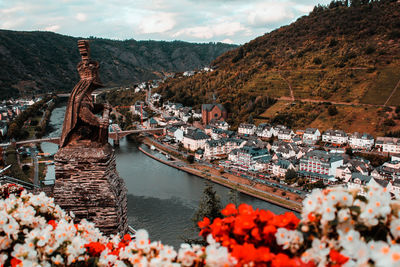 Knight statue at reichsburg castle overlooking town and river surrounded by flowers
