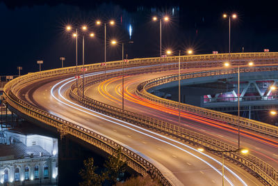 Highway at night lights. fast car light path, trails and streaks on interchange bridge road. night