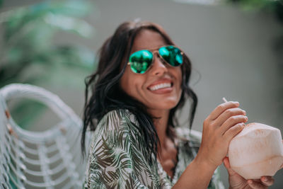 Portrait of a smiling young woman holding sunglasses