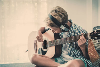 Midsection of man playing guitar