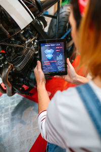 Mechanic woman using engine diagnosis app to review motorcycle