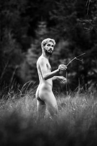 Naked young man standing on field