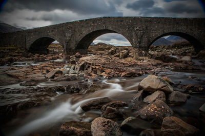 Arch bridge over river against sky